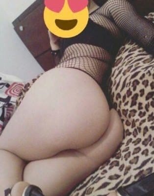 Person lying on a leopard‑print bed wearing fishnet stockings; a colorful emoji overlays the upper body to obscure the face.