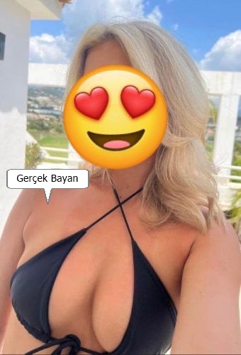 Selfie of a woman in a black bikini on a sunny balcony, face covered by a heart‑eyes emoji; speech bubble reads 'Gerçek Bayan'.